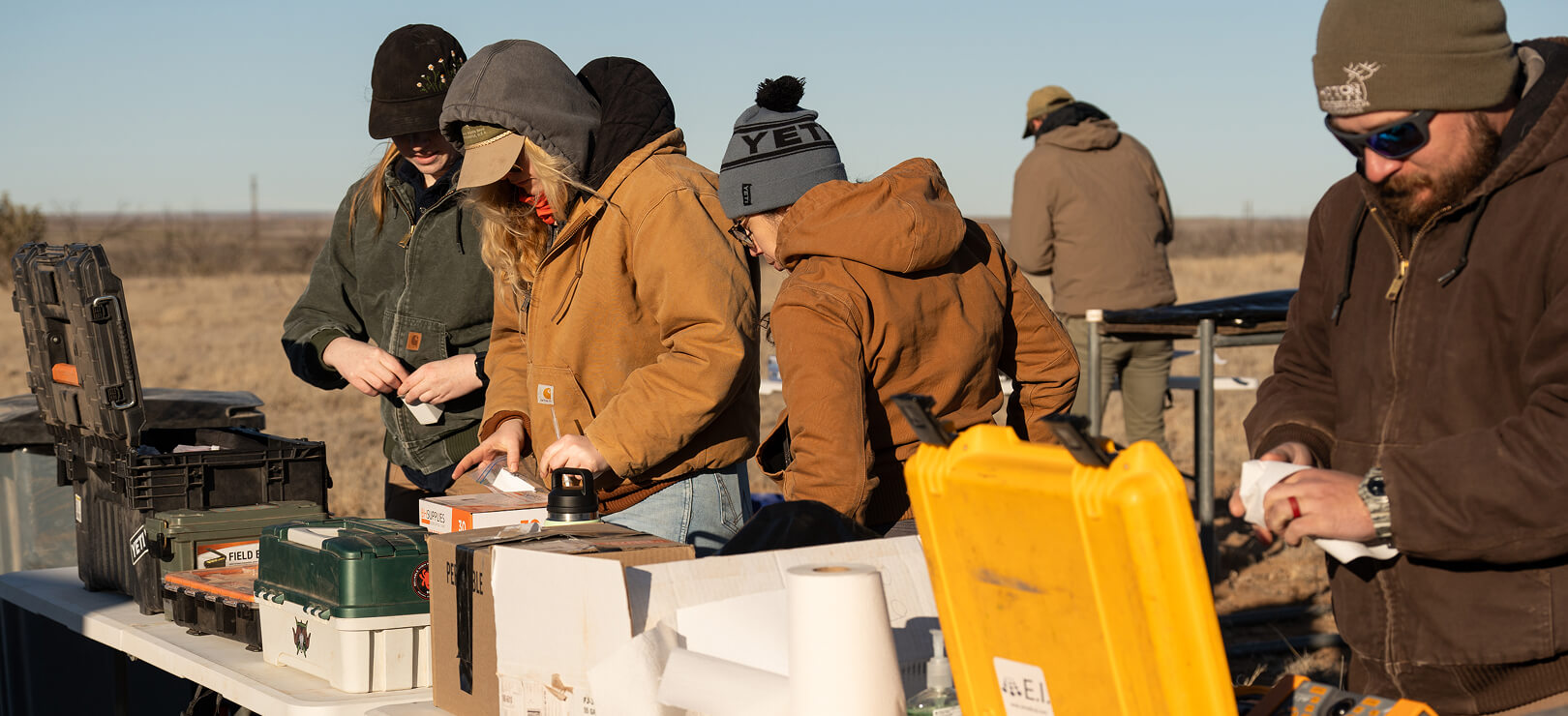 A diverse team of wildlife biologists organizes gear in a field