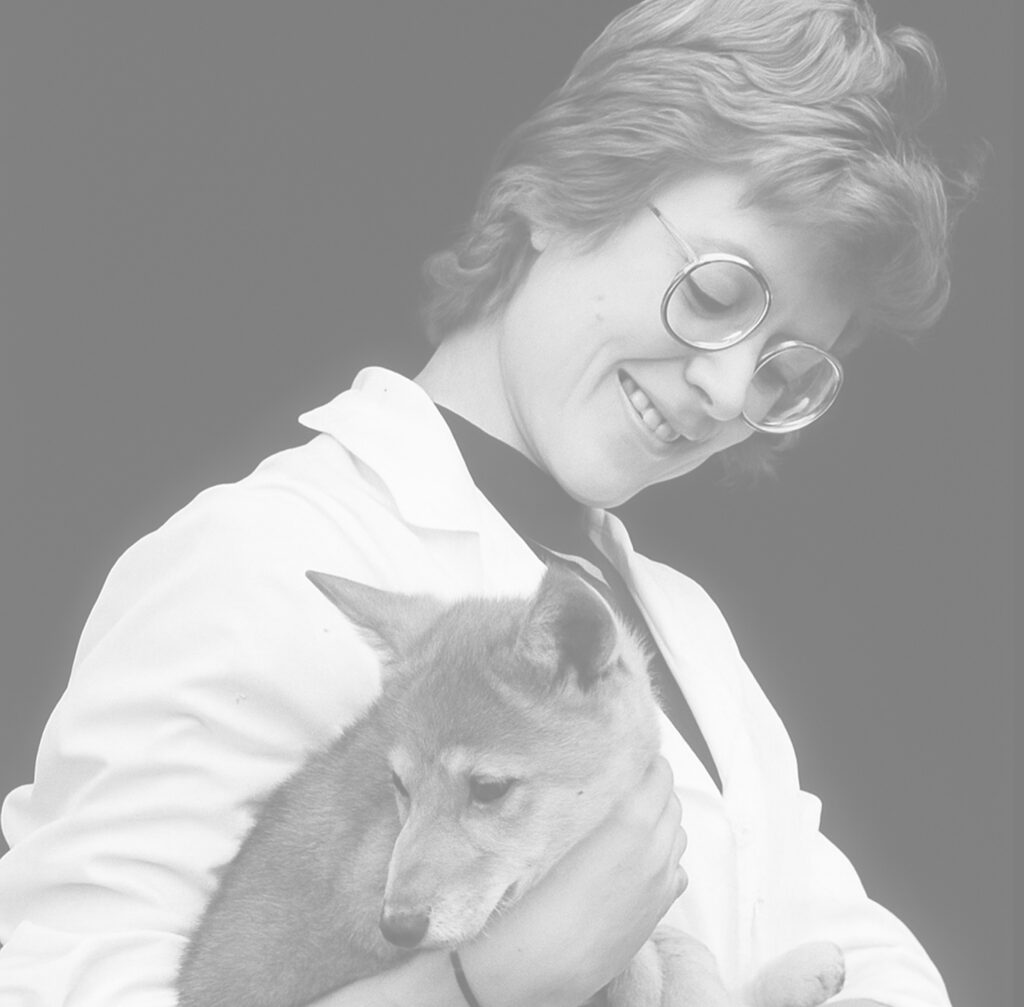 Dianna Hallet, the first female president of The Wildlife Society, holds a small coyotes while wearing a white coat