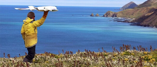 A wildlife researcher launches a fixed-wing conservation drone on the remote sub-Antarctic