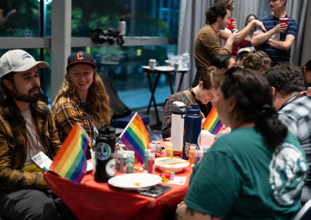 A table of conservation professionals sit at a table filled with pride flags and art supplies, participating in an icebreaker activity at The Wildlife Society's annual conference