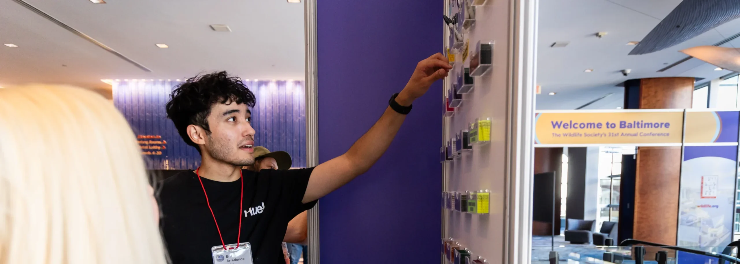 Conference attendee interacting with a wall-mounted display during a professional networking event inside a modern conference venue.