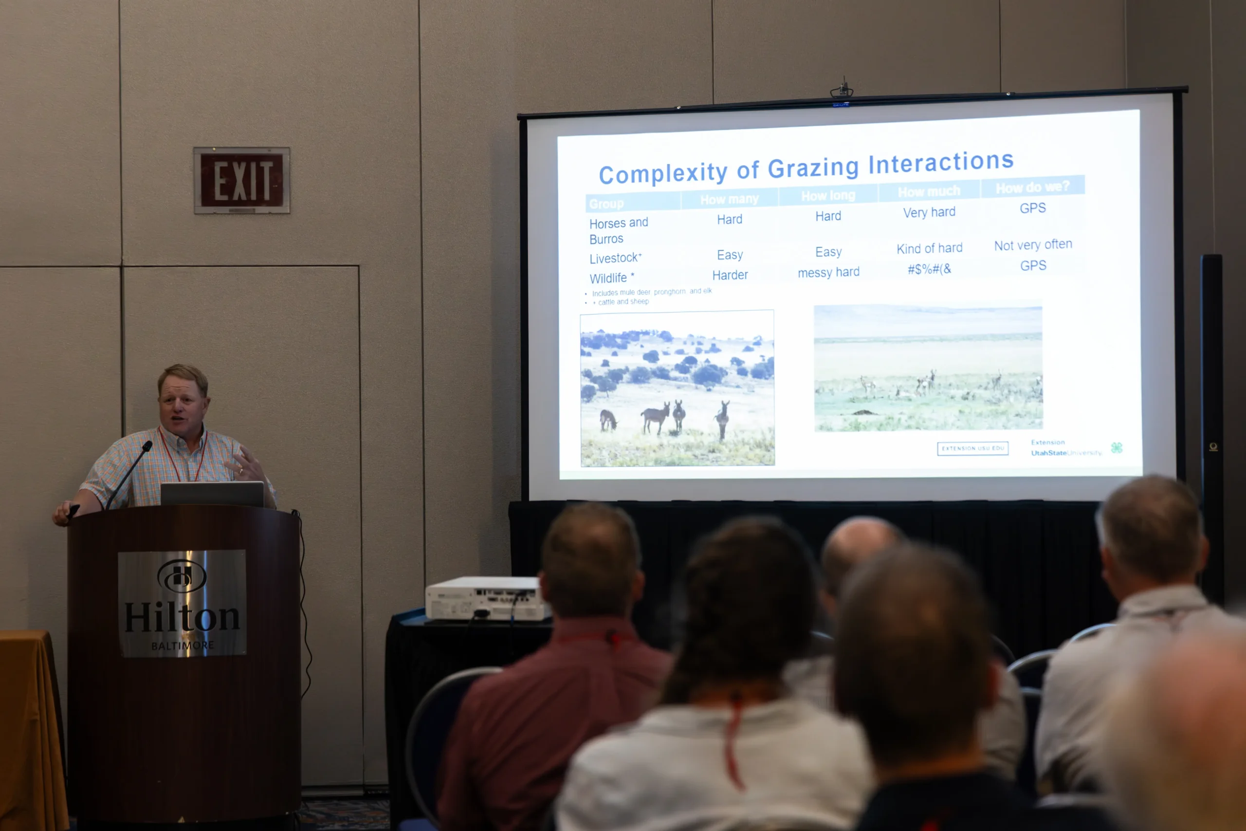 Researcher presenting a scientific talk on wildlife grazing interactions at an environmental conference with an audience and projected data slides.