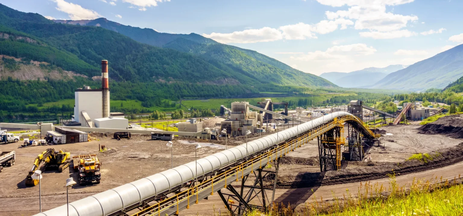 Oil and gas industrial facility in a mountain valley showing habitat disturbance and infrastructure development in wildlife areas.